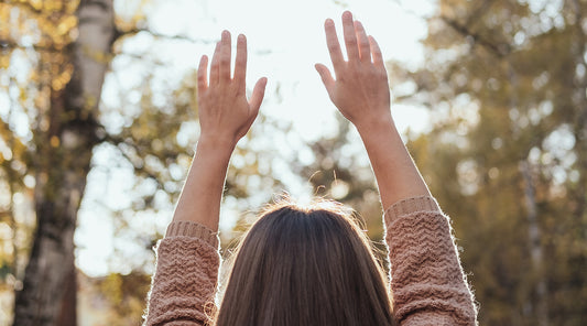 A woman hold her hands up to the sky in happiness.